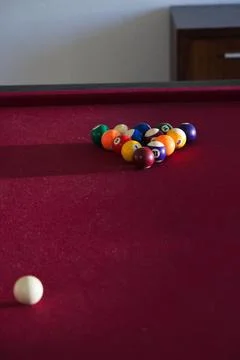Triangular rack of colorful billiard balls sitting on maroon pool table near 库存照片