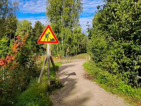 A triangular road sign indicating pathway reconstruction stands beside a dirt Stock Photos