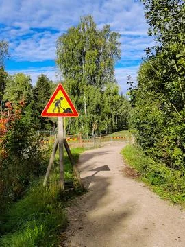 A triangular road sign indicating pathway reconstruction stands beside a dirt Stock Photos