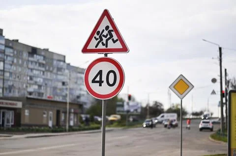 Triangular road sign warns drivers about children crossing near school. Stock Photos