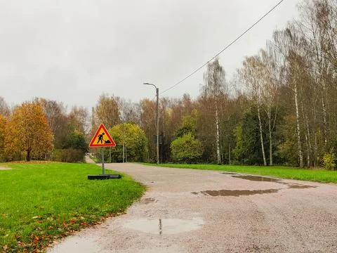 A triangular road work sign warning of construction is placed on a metal base Stock Photos
