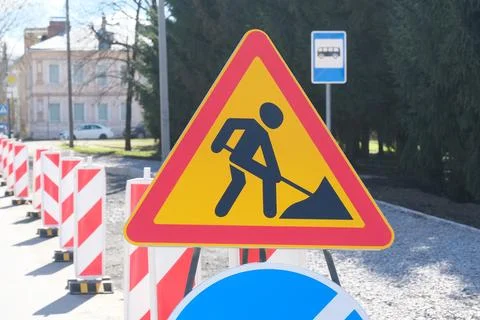 Triangular road work warning sign placed on a city street with safety barri.. Fotos de archivo