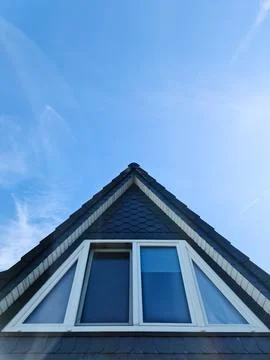 Triangular roof window overlooking blue sky with clouds 스톡 사진
