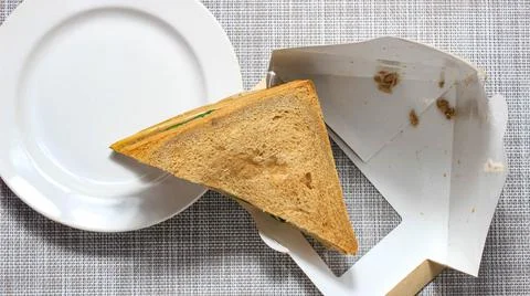 A triangular sandwich that is pulled out of the package into a plate. 스톡 사진
