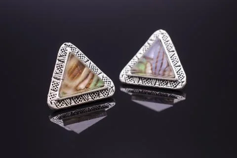 Triangular silver earrings with marble isolated on black Foto stock
