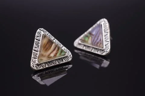 Triangular silver earrings with marble isolated on black 写真素材