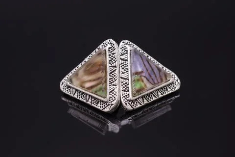 Triangular silver earrings with marble isolated on black 스톡 사진