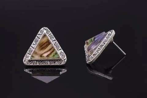Triangular silver earrings with marble isolated on black Stockfoto's