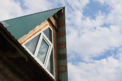 Triangular skylight of an attic of a village log house under construction aga Stock Photos