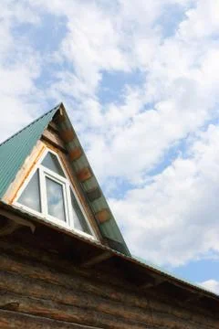 Triangular skylight of an attic of a village log house under construction aga Stock Photos