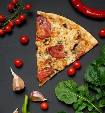 Triangular slice of baked pizza with mushrooms, smoked sausages, tomatoes a.. Stock Photos