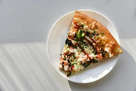 Triangular slice of pizza on a white plate Foto stock