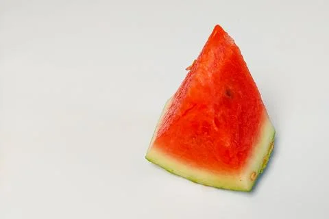 A triangular slice of red watermelon with juicy flesh on a white background. Stock Photos