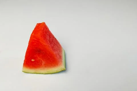 A triangular slice of red watermelon with juicy flesh on a white background. Stock Photos