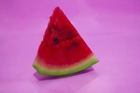 A triangular slice of red watermelon on a pink stink. Stockfoto's