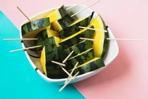 Triangular slices of ice cream on a stick of ripe yellow watermelon in a plat Stock Photos