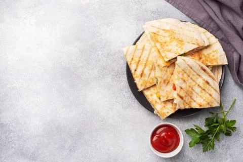 Triangular slices of a Mexican quesadilla with the sauce. The traditional d.. Foto stock