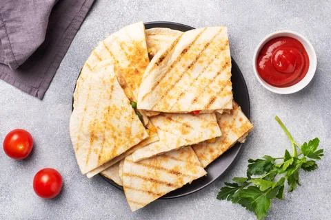 Triangular slices of a Mexican quesadilla with the sauce. The traditional d.. Foto stock