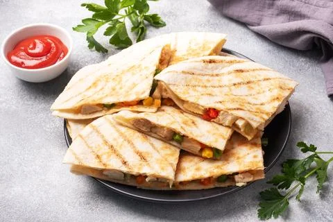 Triangular slices of a Mexican quesadilla with the sauce. The traditional d.. Foto stock