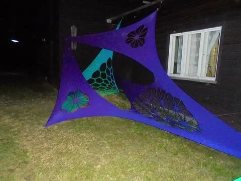 Triangular stretch fabric art installation at night beside wooden building Stock Photos