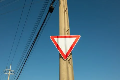 Triangular Traffic Sign on a Utility Pole Against Blue Sky Stock Photos