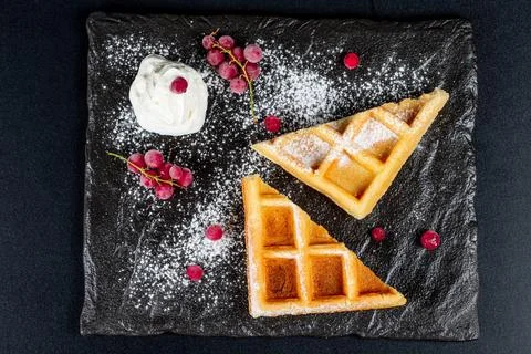 Triangular waffles with currant, powdered sugar and whipped cream on a blac.. Stock Photos