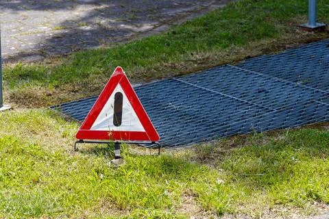 Triangular Warning Sign Near Metal Grate on Grass Stock Photos