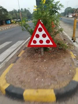 A triangular warning sign with red dots on a road median 스톡 사진