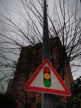 A triangular warning sign for traffic lights attached to a pole, set against a Fotos de archivo