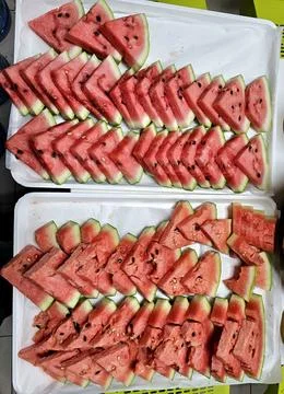 Triangular watermelon slices arranged on a white tray, showcasing the vibrant Stock Photos