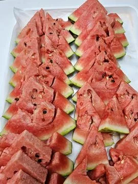 Triangular watermelon slices arranged on a white tray, showcasing the vibrant Stock Photos