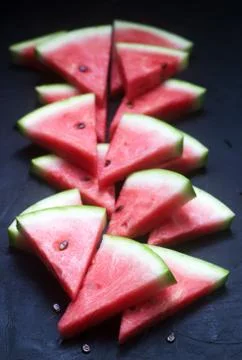Triangular watermelon slices with seeds on a black concrete background. 写真素材