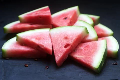 Triangular watermelon slices with seeds on a black concrete background. Foto stock