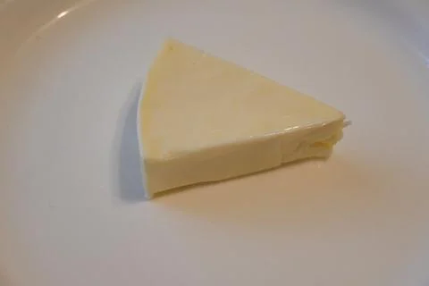 Triangular wedge of soft cheese on a plate Stockfoto's