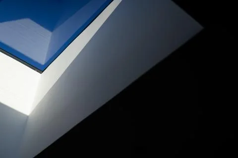 Triangular white ceiling forming skylight, framing blue sky through clear glass 스톡 사진