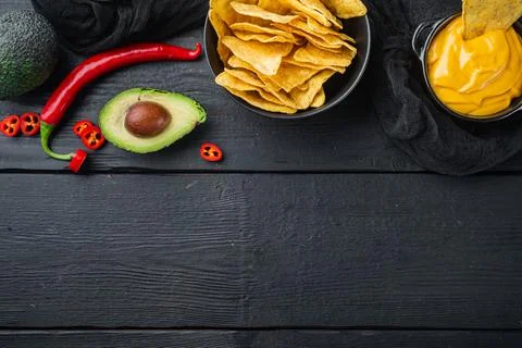 Triangular yellow corn tortilla chip with sauce, on black wooden background,  스톡 사진