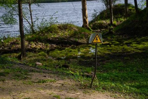 Triangular yellow dangerous electrical voltage sign on a metal rod. Stock Photos