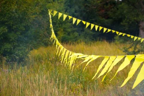 Triangular yellow flags decoration stretched across a grassy meadow near the  Stock Photos