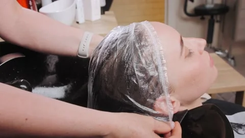 Trichologist puts transparent cap on client head for mask Video stock 196854795