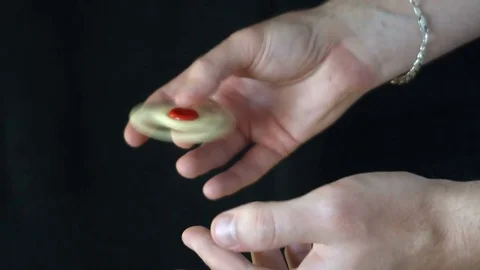 The trick with the hand spinner on a black background,the young man throws the Stock Footage 76634539