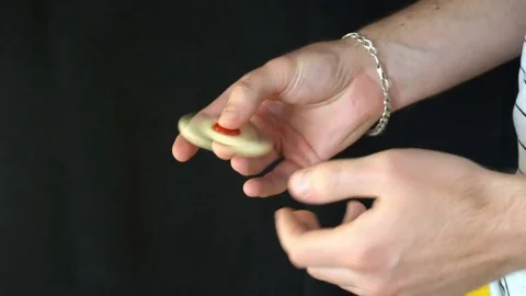 The trick with the hand spinner on a black background,the young man throws the Stock Footage 76634816