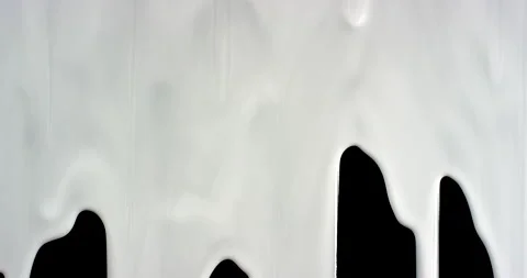 Trickles of spilled white liquid flow down the black background. Isolated white 動画素材 171828018