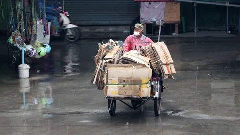 A tricycle with a load of used cardboard packaging drives along the wet road Stock Footage 219481996
