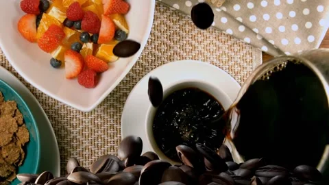 Triggered by falling beans, white coffee cup filling from carafe, beans Video stock 337904982