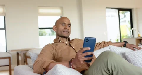 Triggered by picking up smartphone, man scrolling screen, smiling and reclining Stock Footage 336609321