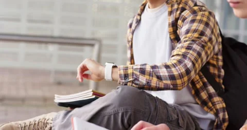 Triggered by smartwatch vibrating student is donning headphones, writing study Stock Footage 335453975