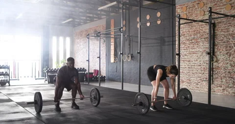 Triggered by workout plan Diverse gym partners lifting barbells for strength at Video stock 313938995