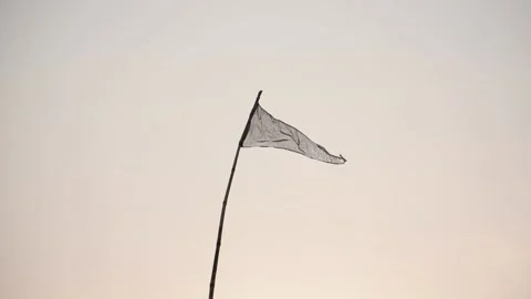 A trigonal flag waving in wind up the sky attached to a stick in front of whi Stock Footage 131078496
