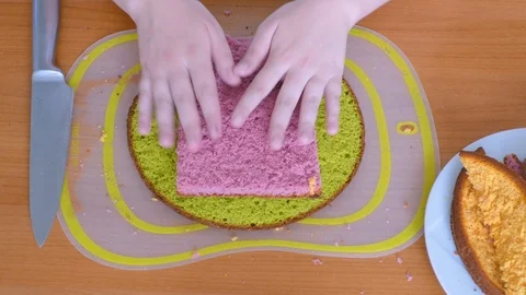 Trim sides from biscuit colored cake using another cake per example 스톡 동영상 123576667