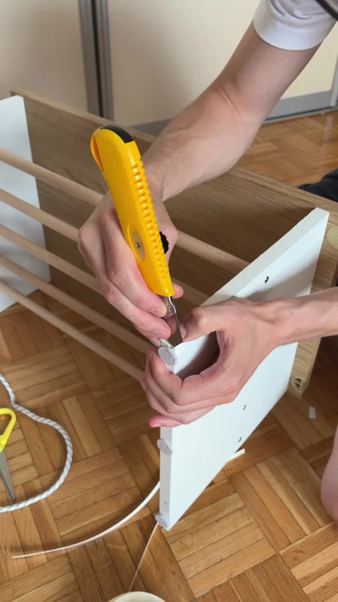 Trimming excess edge banding with utility knife during DIY furniture assembly Stock Footage 340071121